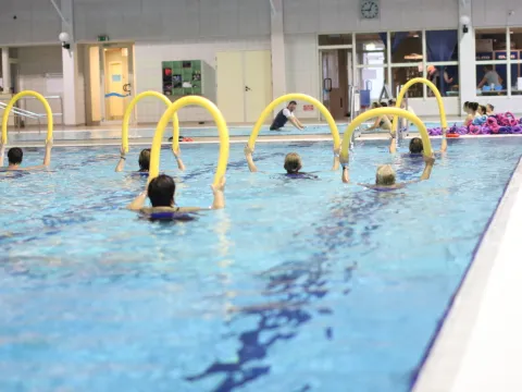 Männer und Frauen im Wasser bei einer Wassergymnastik